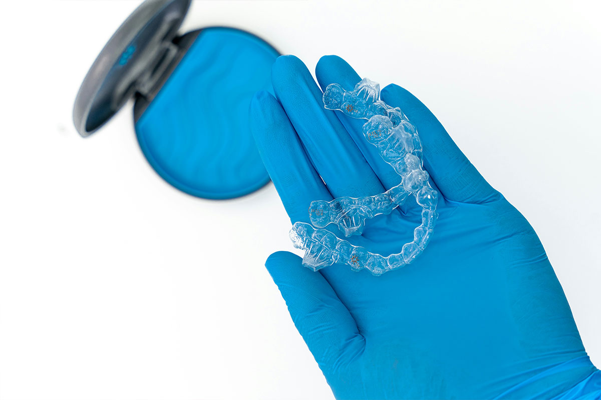 Dentist holding Invisalign retainer with a case in background